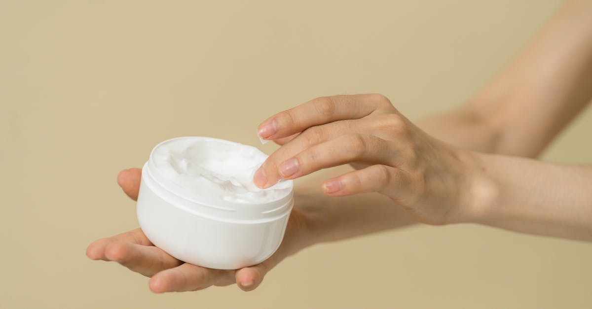 A person applying facial moisturizer to their cheek